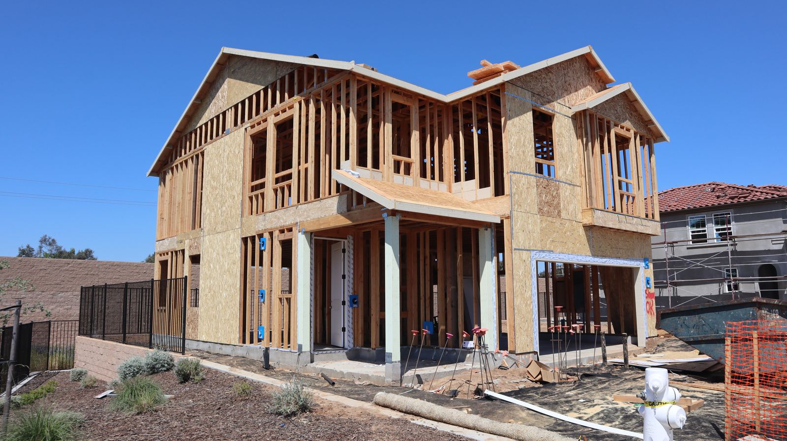 A two-storey house under construction, still open framing, before sheathing and drywall.