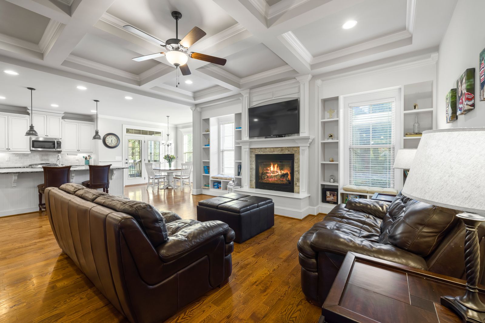 An expensive great room with a coffered ceiling peppered with recessed downlights and a ceiling fan light, everything flatly and evenly lit.