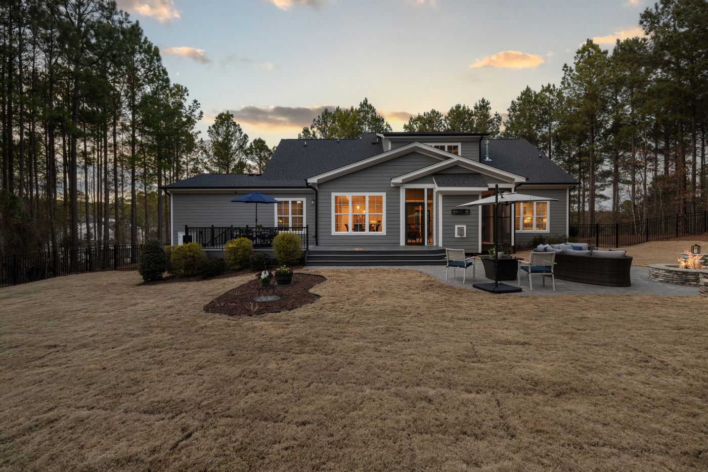 An ordinary suburban house at dusk with its exterior and interior lighting on.